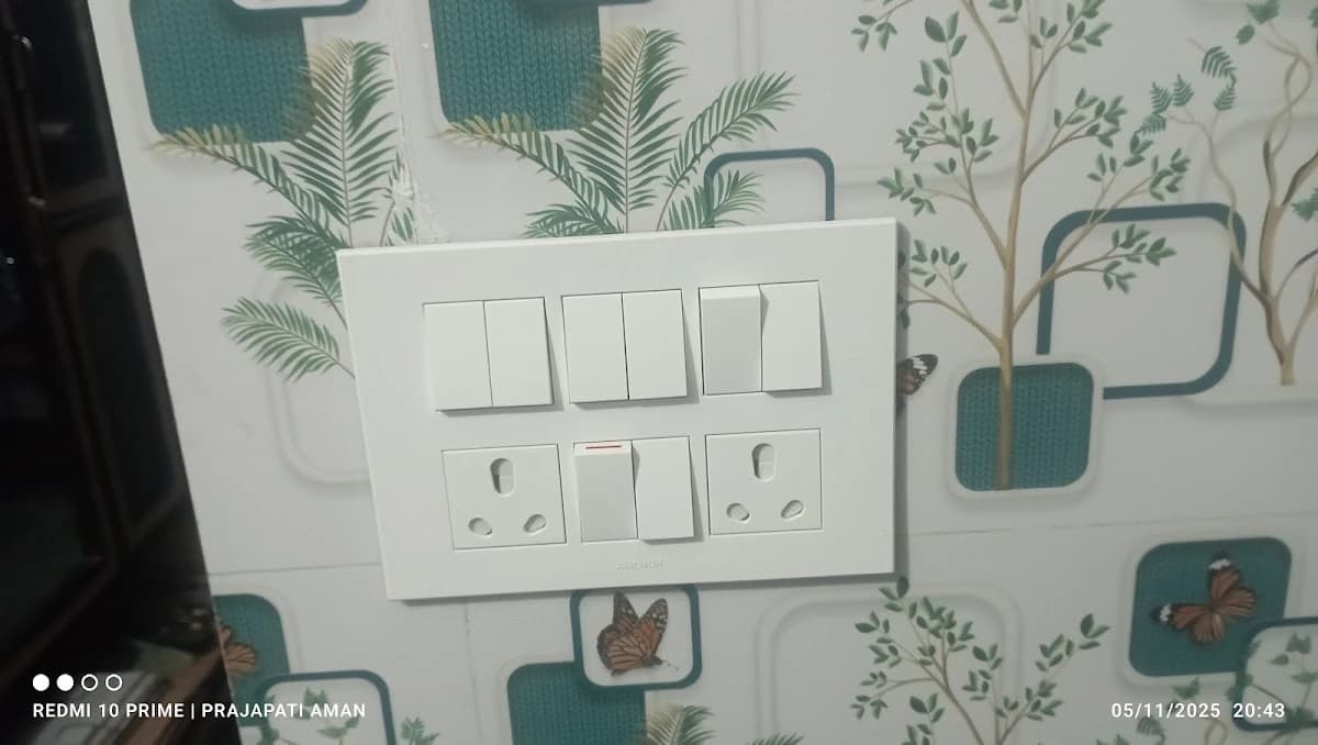 Clean white modular switch board with multiple switches installed on wallpaper wall in Lucknow by Prajapati Electrical