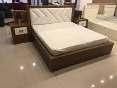 Premium designer bed with upholstered headboard and matching side tables at furniture showroom in Lucknow by Prajapati Electrical