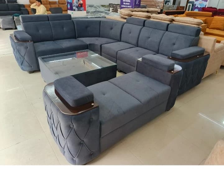 Premium grey tufted L-shape sofa set with glass center table at furniture showroom in Lucknow by Prajapati Electrical