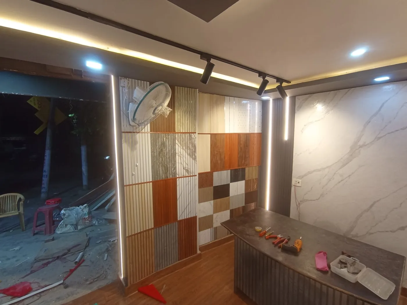 Showroom with tile and panel display wall, wall fan, marble panel and reception desk in Lucknow by Prajapati Electrical