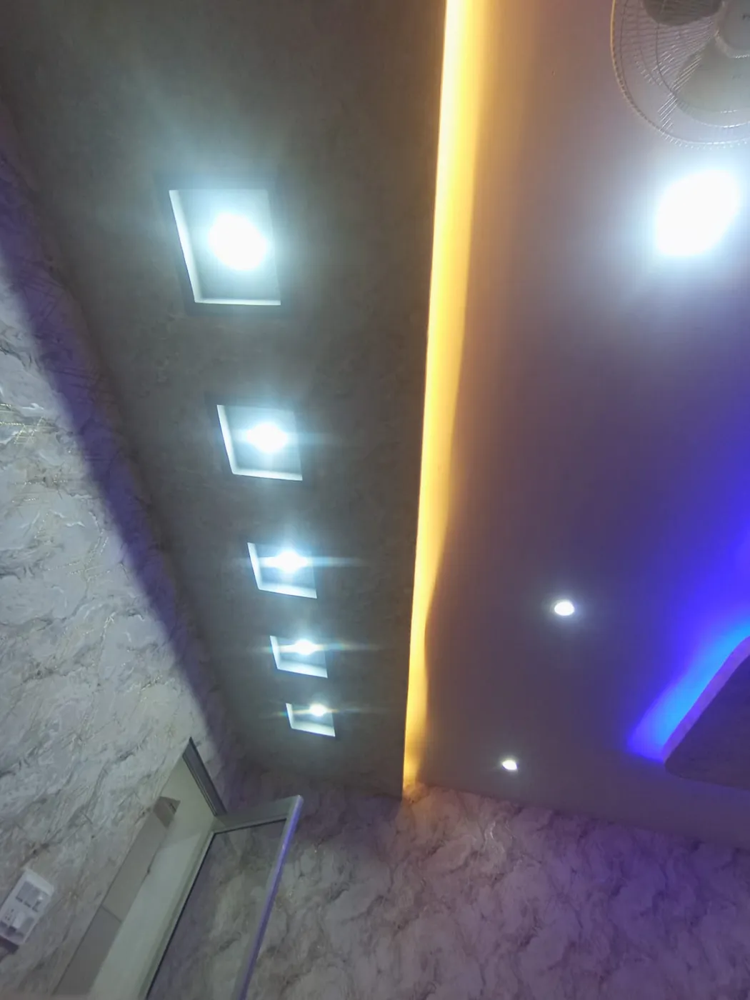 Designer false ceiling with recessed square LED lights and yellow-blue cove lighting in Lucknow by Prajapati Electrical