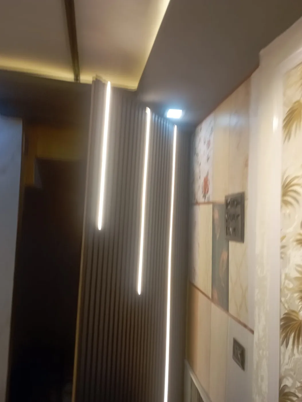 Grey fluted wall panel with vertical LED profile lights for a modern corridor in Lucknow by Prajapati Electrical