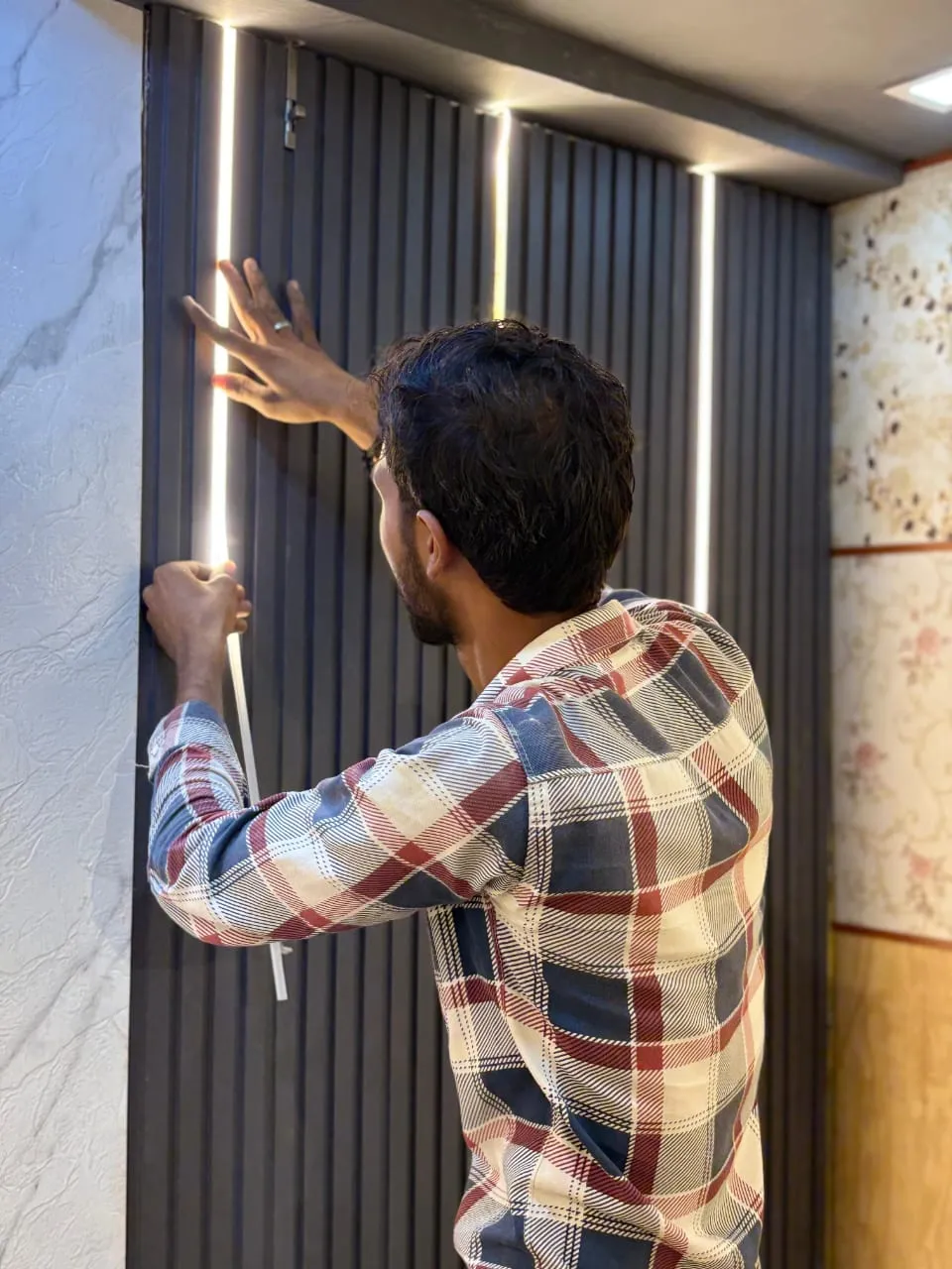 Electrician installing vertical LED profile strip lights on a fluted panel wall in Lucknow by Prajapati Electrical